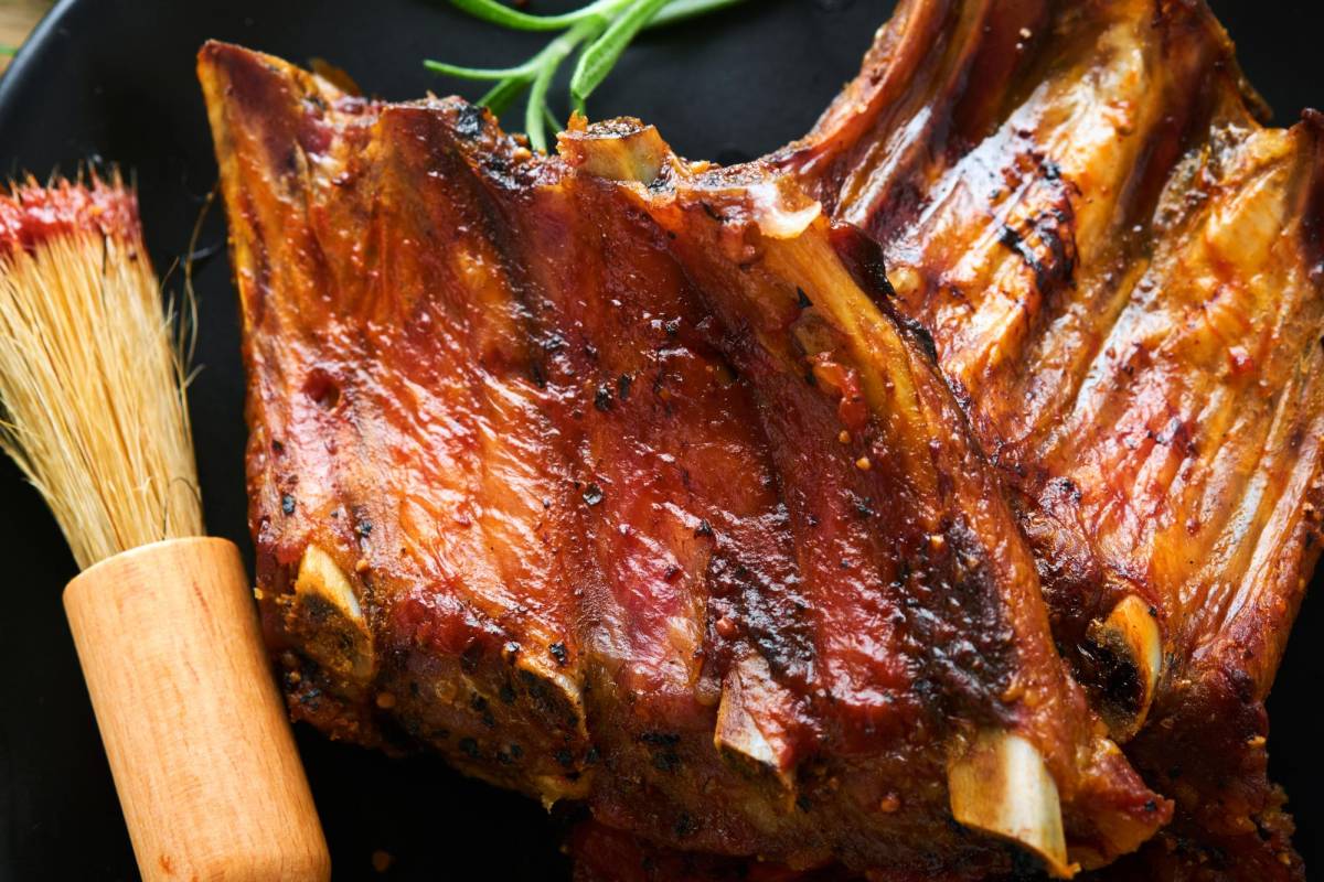 $!Grilled and smoked pork ribs with barbeque sauce on an old vintage wooden cutting board on old wooden table background. Tasty snack to beer. American food concept. Top view.