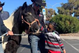 Tim O’Connell ayuda a King James, de 5 años, a conocer a un caballo llamado César, durante la visita anual del Wrangler NFR a la Fundación de Autismo Grant-a-Gift.